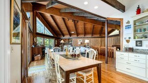 Spaziosa sala da pranzo con tavolo e sedie in legno, cucina con mobili bianchi e soffitto a volta.