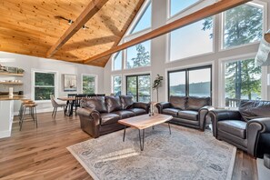 Un salon spacieux avec un plafond haut, de grandes fenêtres et une vue sur un lac.