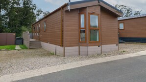 A single-story, brown wooden cabin with a sloped roof, a small porch, and a satellite dish. - Bock Retreat (Morpeth)