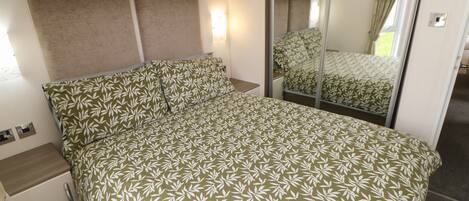 Un dormitorio con cama, armario, espejo y mesita de noche.
