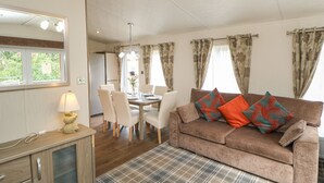 A cozy living room with a sofa, dining table, chairs, and a plaid rug. - Bock Retreat (Morpeth)