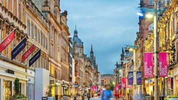 A cobblestone street lined with historic buildings, some with 'SALE' banners, and a few with 'HOUSE OF FRASER' signs.