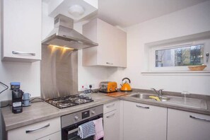 A modern kitchen with stainless steel appliances, a window above the sink, and a view of the outside.