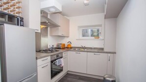 Una cocina moderna con armarios blancos, estufa a gas, microondas y ventana sobre el fregadero.