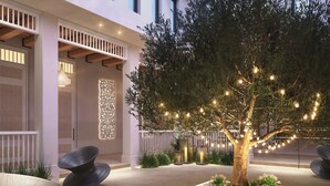 A modern outdoor seating area with a tree, decorative lights, and a white fence. - Maysan Doha, LXR Hotels & Resorts (Doha)