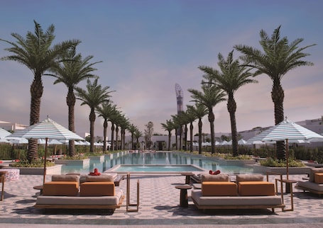 Una piscina al aire libre, sombrillas, sillones reclinables de piscina