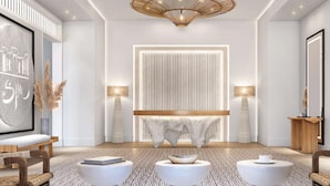 A modern interior with a central seating area, a large artwork on the left, and a mirror on the right. - Maysan Doha, LXR Hotels & Resorts (Doha)