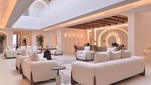 A spacious, modern living area with white sofas, a round coffee table, and a staircase leading to an upper level. - Maysan Doha, LXR Hotels & Resorts (Doha)