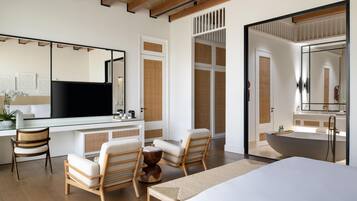 Una habitación de hotel moderna con una cama grande, dos sillones, un escritorio, un televisor de pantalla plana, un espejo grande y una bañera.