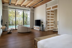 A modern bedroom with a large bed, a TV, a sofa, and a view of a swimming pool.