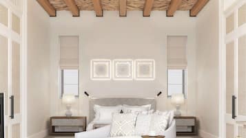 Un dormitorio amplio con una cama grande, dos mesitas de noche con lámparas, un sofá blanco y un techo con vigas de madera.
