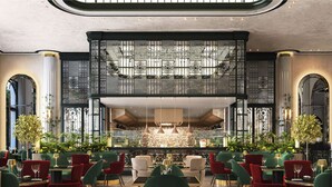 A spacious indoor dining area with multiple tables and chairs, a central bar area, and decorative plants. - Maysan Doha, LXR Hotels & Resorts (Doha)