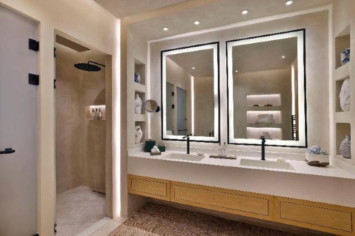 A bathroom with a double vanity, a large mirror, and a walk-in shower.