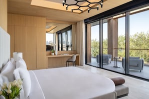 A modern bedroom with a large bed, a desk, and a balcony with seating. - Katara Hills Doha, Lxr Hotels & Resorts (Doha)