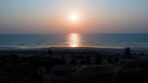 A sunset over a beach with a small house in the foreground. - SPARV Aulakhs Resort (Mandrem)