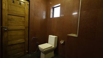 Une salle de bain avec une porte en bois, des toilettes et une petite fenêtre.