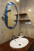 Un baño con un lavabo blanco, un espejo con diseños azul y blanco, y un dispensador de jabón.