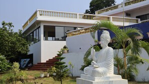 A white building with a statue of a seated figure in front. - SPARV Aulakhs Resort (Mandrem)