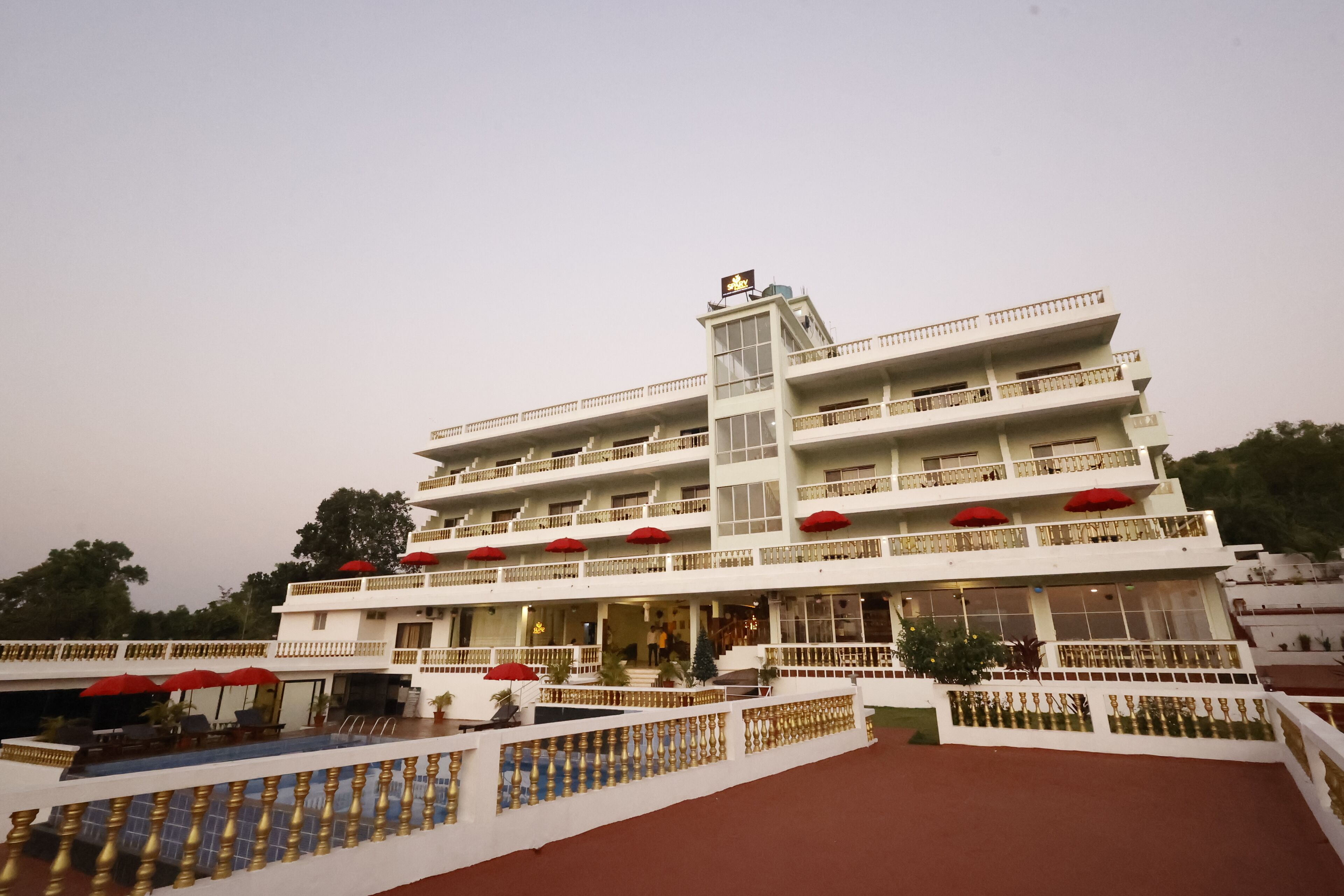 Um hotel com vários andares, varandas, área de estar coberta ao ar livre e entrada central.
