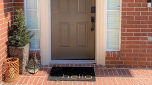 Uma porta marrom com uma coroa de flores e um tapete com a palavra 'hello'.