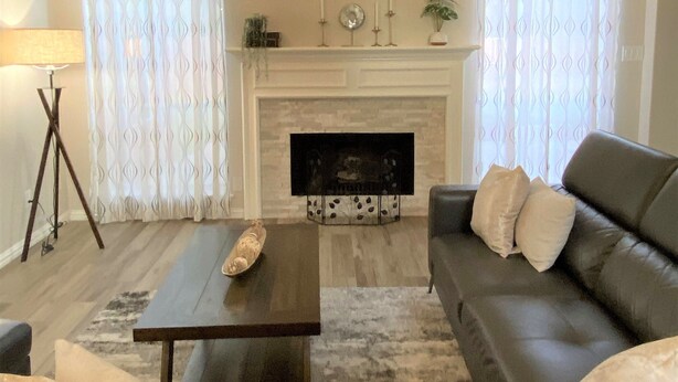 Uma sala de estar com lareira, sofá, mesa de centro e cortinas.