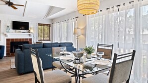 Uma sala de estar moderna com uma mesa de jantar de vidro, sofá azul e lareira.