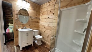 Casa de banho de cabana de madeira compacta, com lavatório, sanita e chuveiro.