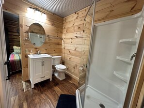A compact wooden cabin bathroom with a sink, toilet, and shower. - Romantic Red River Gorge Cabin • Hot Tub • Quiet Escape (Stanton)