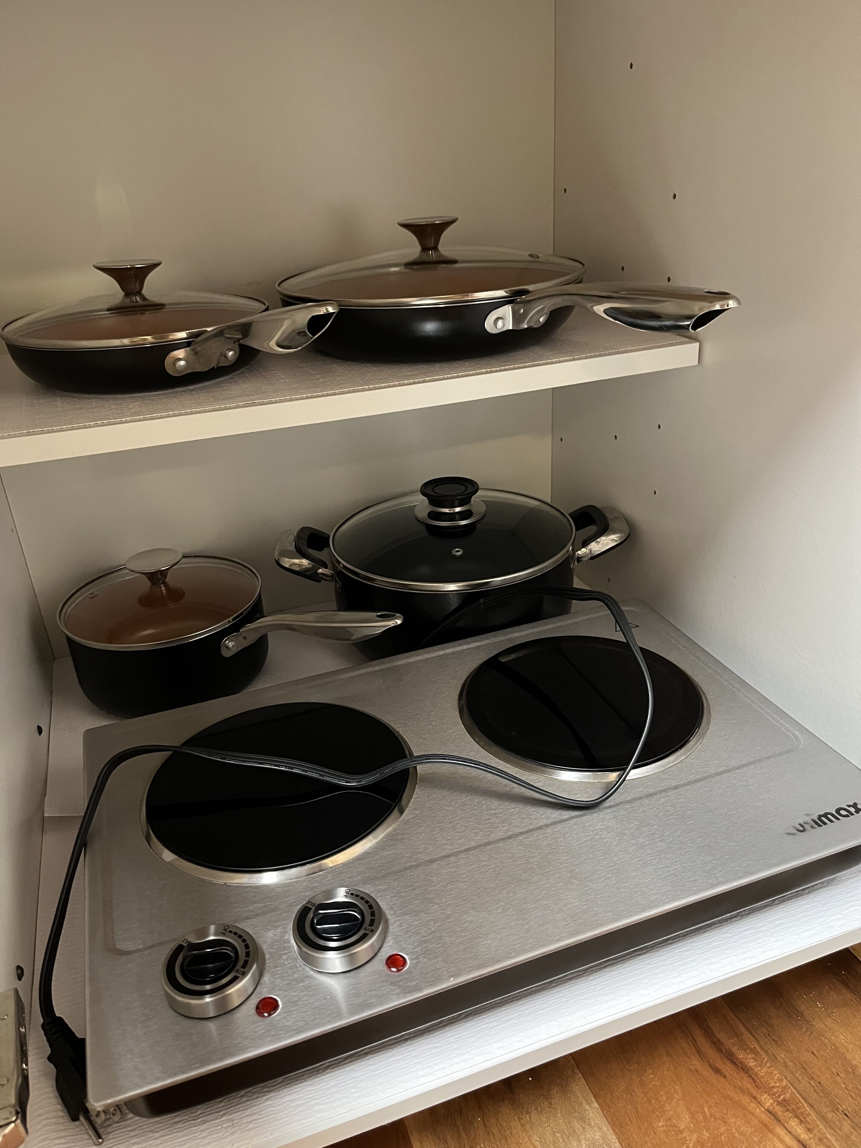 A kitchen with a stove, pots, and pans on shelves.