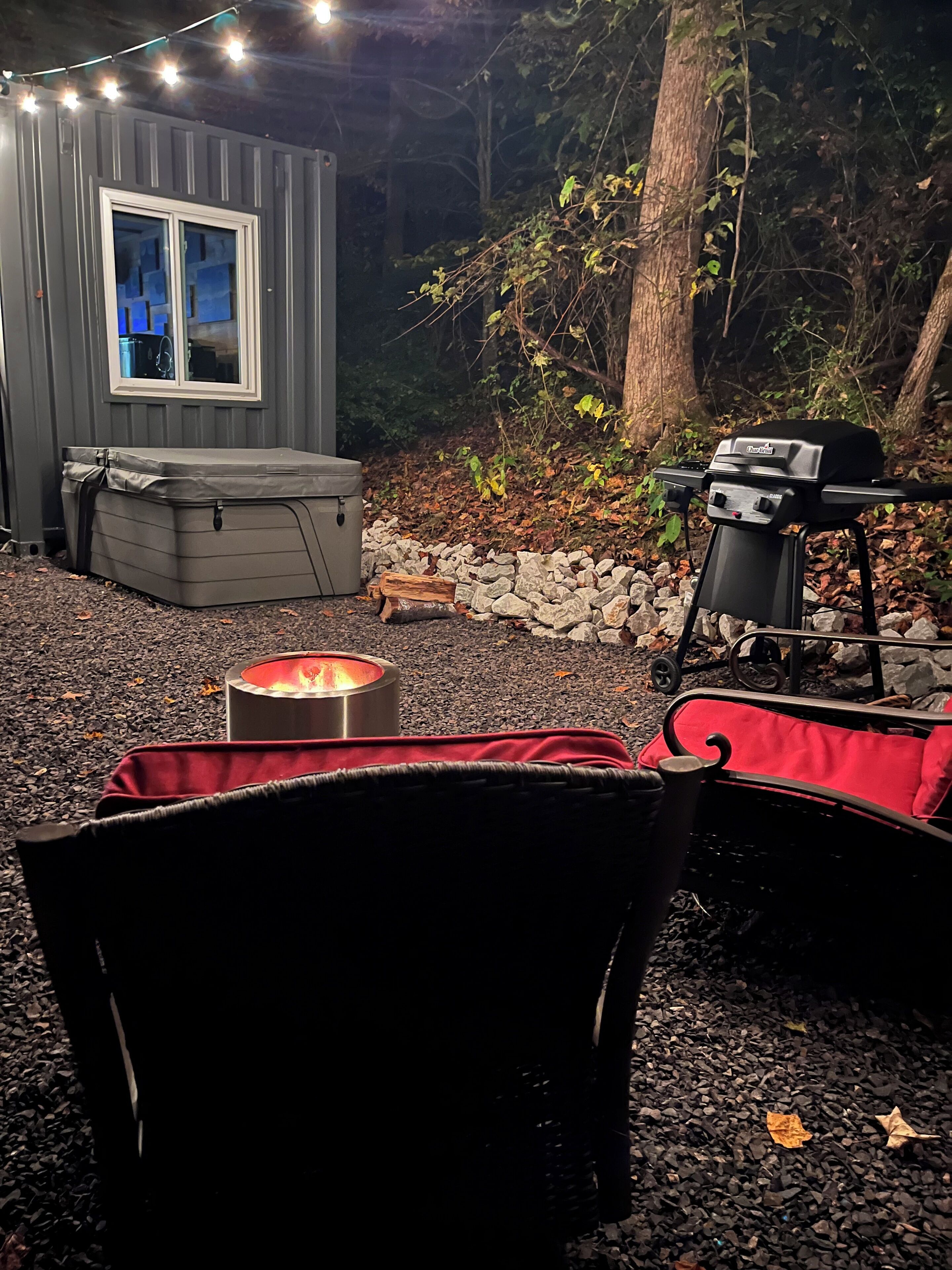 Un espacio al aire libre acogedor con una chimenea, una parrilla y un pequeño muro de piedra.