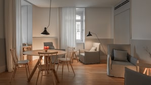 Una sala moderna con una mesa redonda de madera, dos sillas, un sofá y una lámpara de pie.
