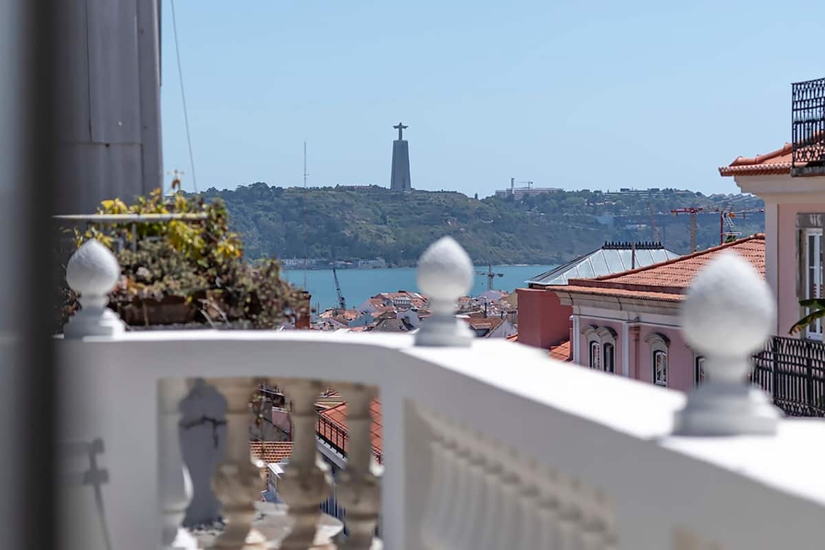 A balcony with a view of a distant hill and a church.