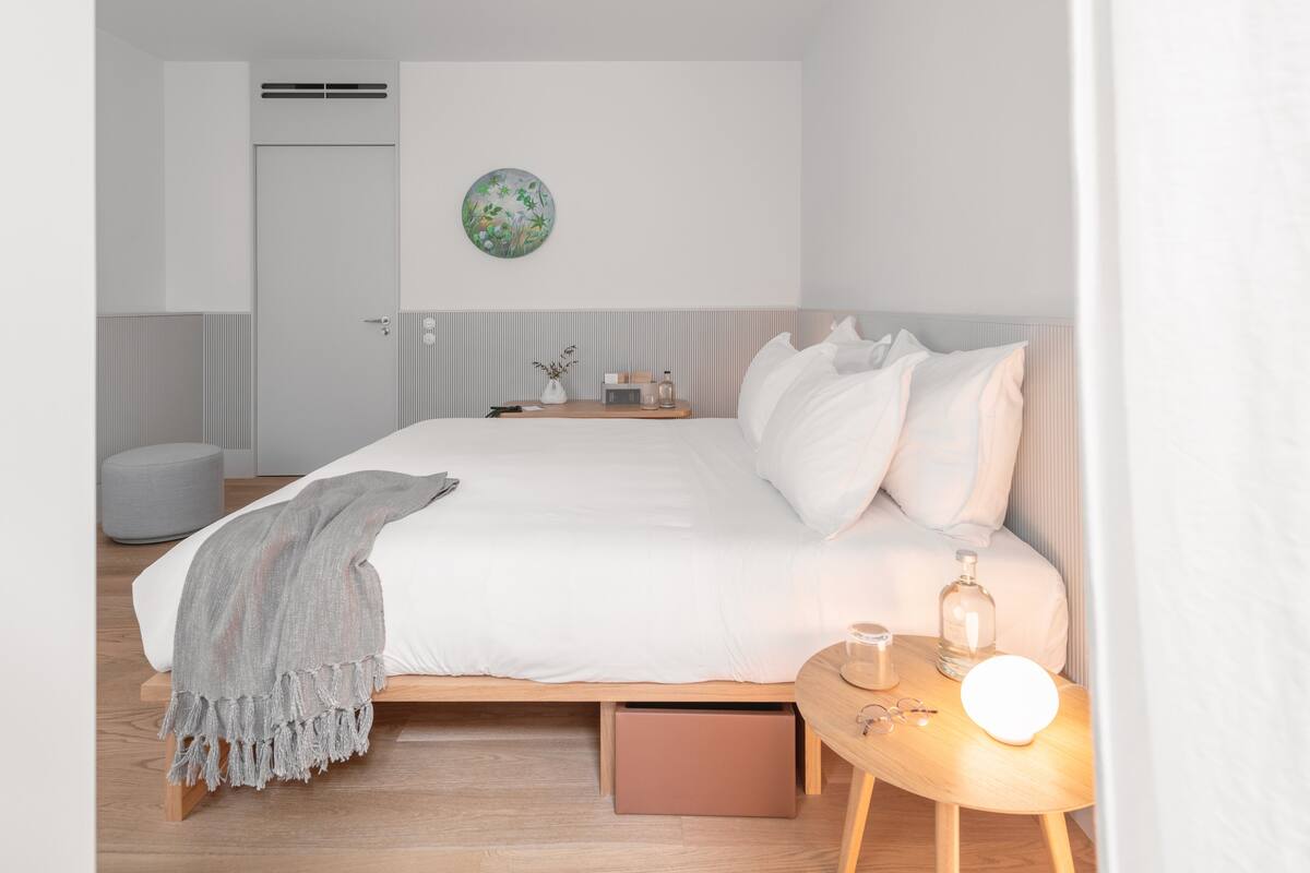 A modern bedroom with a bed, bedside table, and a wall-mounted decorative plate.
