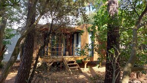Una cabaña de madera con un porche, rodeada de árboles.