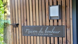 Una pared de madera con un letrero que dice "Maison du bonheur" y una pequeña lámpara.