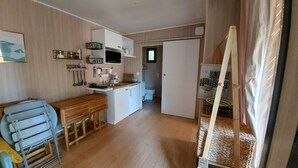 Una cocina compacta con comedor, un baño pequeño y una zona de descanso con cama y cortinas.