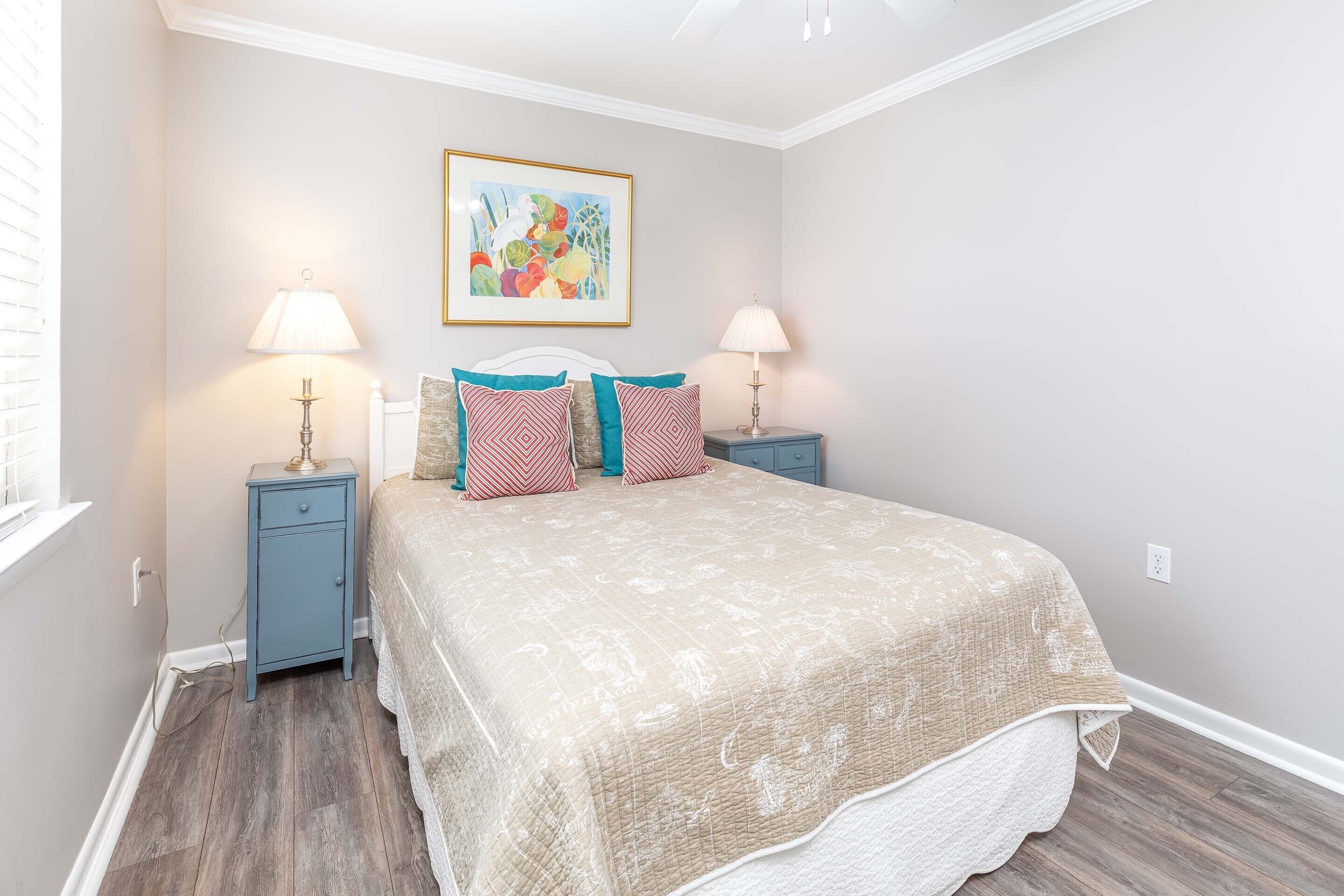 A bedroom with a bed, two nightstands, two lamps, a wall art piece, and a window.
