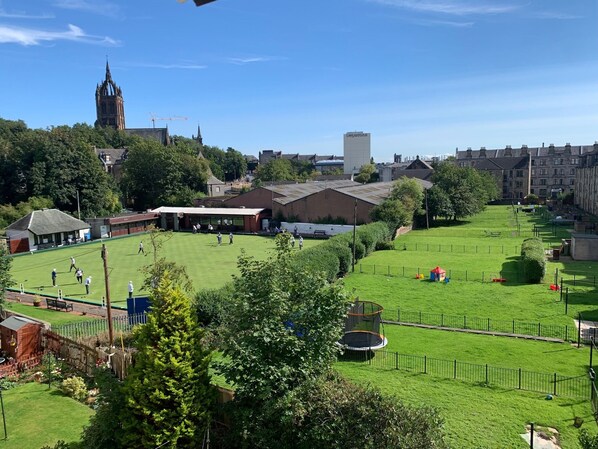 A large green field with a playground and a building with a sloped roof.
