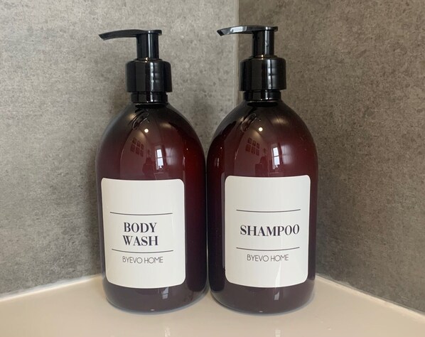 Two bottles of body wash and shampoo with pumps, placed on a countertop.