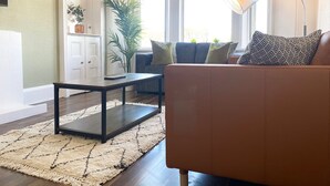A living room with a sofa, a coffee table, a lamp, and a large window.