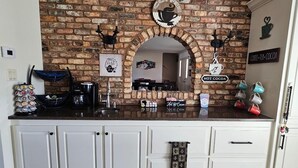 A kitchen with a brick wall, white cabinets, and a coffee-themed decor.
