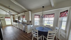 A spacious kitchen with white cabinetry, a dining table with chairs, and a chandelier.