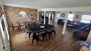 A spacious living area with a pool table, a dining table, and a blue sofa.