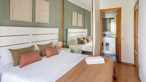 A hotel room with a large bed, a bedside table, a mirror, and a view into the kitchen. - Plaza España 4BD / 2BTH with terrace (Barcelona)