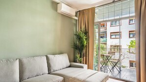 A living room with a sofa, a balcony with a table and chairs, and a view of a building. - Plaza España 4BD / 2BTH with terrace (Barcelona)