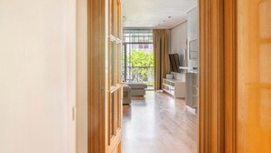 A hallway leading to a living area with a large window, a sofa, and a TV. - Plaza España 4BD / 2BTH with terrace (Barcelona)