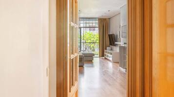 Un pasillo que conduce a una sala de estar con un ventanal grande, un sofá y un televisor.