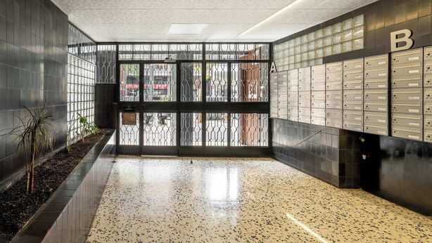 A hallway with lockers, a tiled floor, and a metal gate. - Plaza España 4BD / 2BTH with terrace (Barcelona)