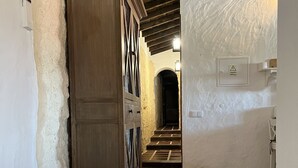 En smal hall med ett träskåp, ett klinkergolv och en trappa som leder till ett annat rum.