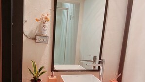 A bathroom with a white sink, a mirror, a potted plant, a small wooden box, and a wicker basket. - 開放式廚房，寬敞自由舒適大空間，鄰近孔廟商圈 (Tainan City)